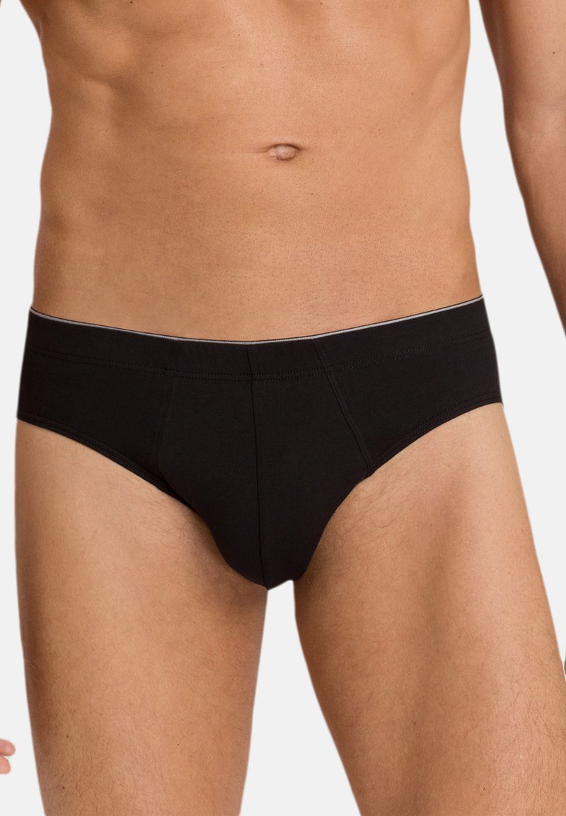 Male torso wearing plain black briefs against a light background, showing waist, abdomen, and upper thighs.