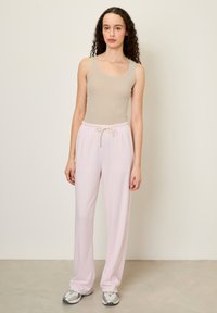 Svetloružové voľné nohavice na doma so šnúrkou v páse, doplnené béžovým tielkom. Hladká tkanina s pohodlným strihom a minimalistickým dizajnom.