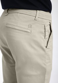 Chino in cotone beige con una vestibilità slim, dotati di una tasca posteriore con un logo ricamato discreto e tasche laterali per funzionalità.