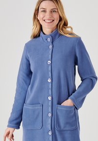 Cardigan largo de forro polar en azul suave, con un cuello alto, botones frontales, detalles bordados y dos bolsillos frontales.