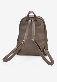 Mochila de imitación cuero marrón con correas ajustables, forma redondeada, cierre de cremallera y dos bolsillos laterales. Textura suave con acentos mínimos.