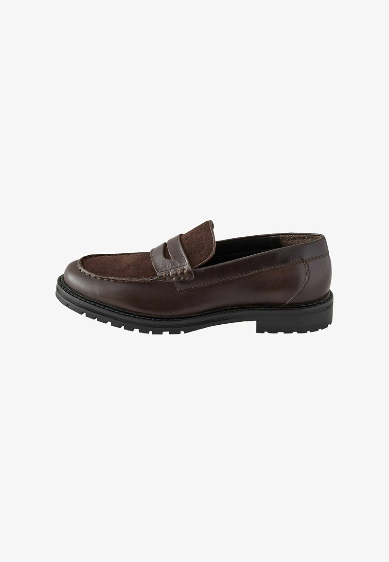 Mocassin pour homme en cuir et daim marron foncé avec une semelle noire robuste et un détail de sangle sur le dessus.