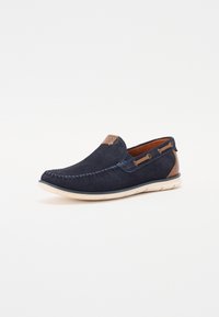 Jūriniai slip-on bateliai su zomšos ir tekstūruoto audinio detalėmis, rudos akcentais, balta padais ir dekoratyvine siuvinėjimo juosta priekyje.