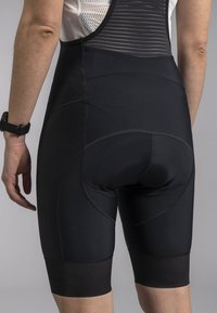 Black cycling shorts with a textured upper panel, padded rear for comfort, and fitted length, featuring contrasting stitching and elastic cuffs.