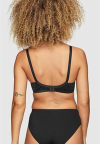 Svart spetsbh med justerbara axelband och hyska stängning, tillsammans med svarta högmidjade trosor, med slät tyg och minimal detaljering.