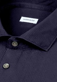 Camicia blu scuro con trama, con bottoni e colletto alla francese, etichetta bianca all'interno con il nome del marchio "seidensticker".
