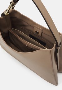 Beige bőr kézitáska puha textúrával, cipzáros rekesszel és patentos záródással. Aranyszínű fémrészek és egyetlen vállpánt.