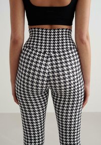 Legginsy z wysokim stanem w wzór pepitki, w kolorach czarnym i białym, o gładkiej fakturze i dopasowanym kroju.