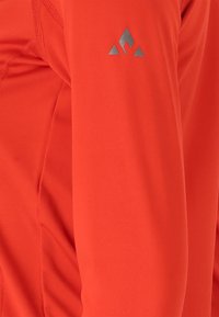 Lys orange langærmet top med glat tekstur; har et sølvfarvet trekantet logo på overarmen og synlige søm. 