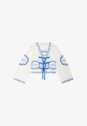 White long-sleeve blouse with blue scalloped trim, embroidered floral patterns, and three blue ribbon ties down the front.