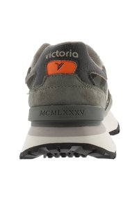 Sneaker verde in suede con accenti grigi, logo sul retro, dettagli arancioni e suola in gomma nera testurizzata. Presenta l'etichetta "MCMLXXXV" sul tacco.