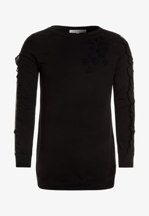 Chemise noire à manches longues avec des applications florales en relief sur le haut de la poitrine et le long des manches.