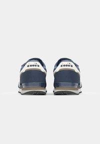Navy blue athletic shoes with white accents, featuring a textured upper, padded collar, and a visible logo on the heel. Rubber sole with grooves.
