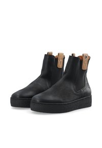 Bottines en cuir noir avec des côtés élastiques, semelle en caoutchouc noir texturé, accents en cuir beige, et languettes en boucle pour un enfilage facile.