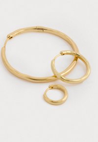 Tre guldfarvede hoops-øreringe i forskellige størrelser. Glatte, afrundede former med en skinnende overflade. De inkluderer en større hoop, en mellemstor hoop og en lille hoop.