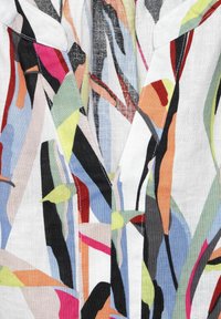 Vícebarevná lněná košile s výstřihem do V, s abstraktními vzory v růžové, černé, zelené a modré na bílém pozadí.