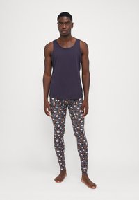 Navy tank top paired with patterned leggings featuring blue, orange, and white designs on a dark background. Fitted design and lightweight fabric.