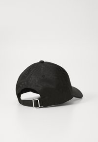 Gorra de béisbol negra con tela texturizada, visera curvada, correa ajustable en la parte posterior y un patrón de logotipos sutil.