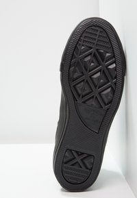 Černá gumová podrážka tenisky s diamantovým vzorem pro lepší grip. Texturované boční části a značkové logo na patě. Ploský, odolný design.