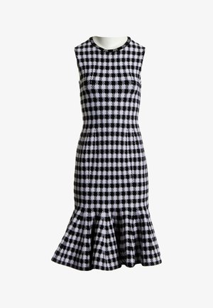 Robe sans manches à carreaux noirs et blancs avec un corsage ajusté et un ourlet volanté évasé.