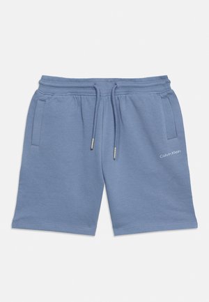 Mėlyni Calvin Klein šortai su raišteliu juosmens srityje ir šoninėmis kišenėmis ant balto fono.