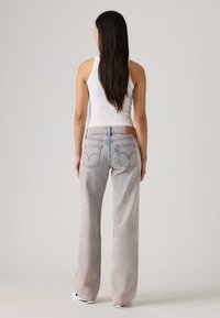 Φωτεινό γαλάζιο τζιν με ίσια γραμμή, ξεθωριασμένη υφή και πίσω τσέπες με εμβληματική ραφή και ετικέτα της μάρκας.