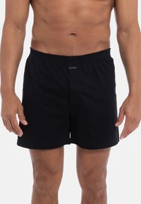 Zwarte katoenen shorts met een elastische tailleband, voorzien van een subtiele merketiket aan de voorkant en een comfortabele pasvorm.
