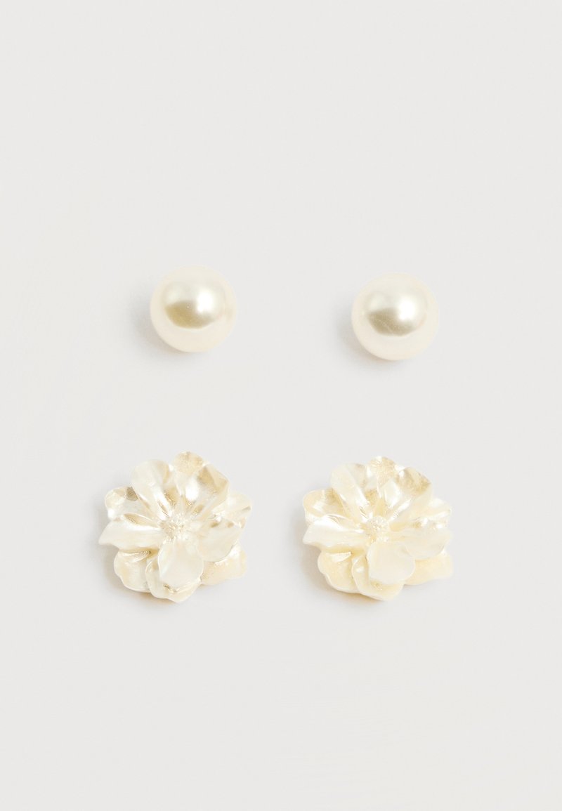 Δύο ζευγάρια σκουλαρίκια τύπου καρφίτσα σε κρεμ χρώμα, ένα στρογγυλό με μαργαριτάρι και ένα σε σχήμα λουλουδιού με υφασμένα πέταλα, πάνω σε απλό λευκό φόντο.