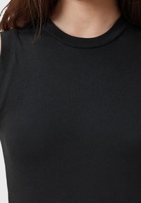 Top nero senza maniche realizzato in tessuto morbido con un design aderente. Presenta un collo alto a giro e cuciture minime.