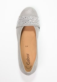 Chaussure plate en daim gris avec un bout arrondi et une bande ornée de strass transparents. L'intérieur affiche la marque et la taille. Texture lisse.