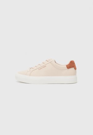 Zapatilla de color rosa claro con parte superior de cuero suave, suela de goma blanca y acento de talón de ante marrón; logo de Calvin Klein en rojo.