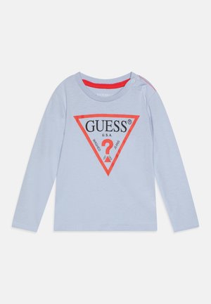 Jasnoniebieska koszulka niemowlęca z długim rękawem, z kołnierzykiem wykończonym czerwonym paskiem, czerwonym trójkątnym logo z przodu z napisem "GUESS" oraz zatrzaskami na ramionach.