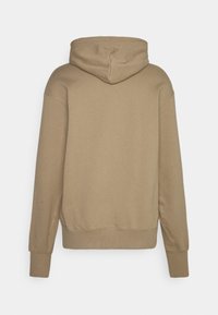 Brun huva sweatshirt med avslappnad passform, ribbade ärmar och nederkant. Slät textur med enkla sömnadsdetaljer längs sömmarna.