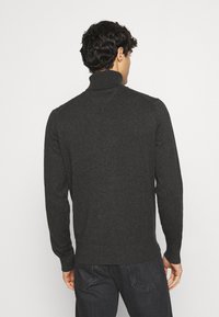 Maglione a collo alto grigio scuro in morbido tessuto a maglia, caratterizzato da maniche lunghe e polsini e colletto a costine, visto da dietro.