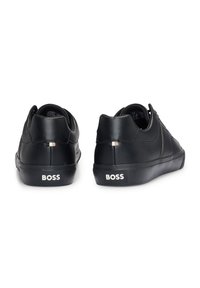 Zwart leren sneakers met ronde neus, gestructureerde bovenkant, gevoerde kraag en rubberen zool. Kenmerkt "BOSS" branding op de hiel.