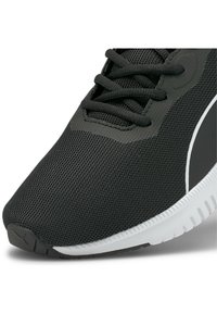 Schwarzer Sportschuh mit Mesh-Obermaterial, texturierter Oberfläche und weißer Gummisohle. Verfügt über schwarze Schnürsenkel und ein schlankes Design mit dezenten Akzenten.
