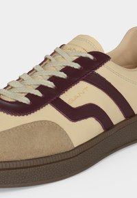 Μπεζ και μπορντό sneakers με κορδόνια, με καπάκι από σουέτ, λαστιχένια σόλα και λογότυπο GANT στη πλευρική επιφάνεια και στη γλώσσα.
