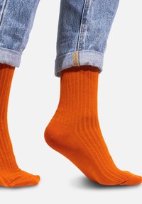 Pomarańczowe skarpetki z prążkowanego bawełnianego materiału, o dopasowanym kroju, z kontrastującą mankietą i gładką teksturą dla komfortu i stylu.