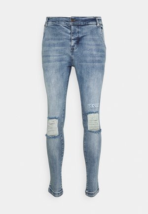 Strakke jeans in lichtblauw denim met versleten plekken op de knieën. Voorzien van een knoopsluiting en subtiele branding op het bovenbeen.