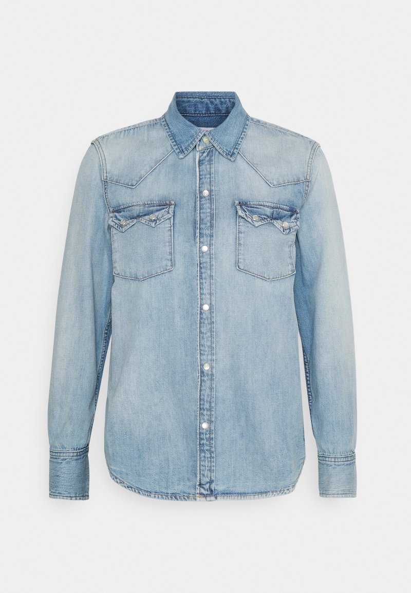 Chemise en denim bleu clair à manches longues, avec fermeture à boutons, deux poches poitrine et détails de découpe western. Texture douce et design classique.