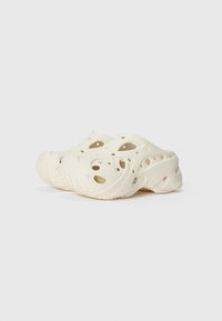 Sabots de style Crocs en blanc cassé, fabriqués en matériau léger avec des trous de ventilation, semelle texturée et design arrondi.