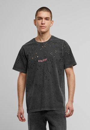 Tricou negru din bumbac cu mai multe găuri mici, guler rotund și text roz "living ICON" pe față; croială lejeră și mâneci scurte.