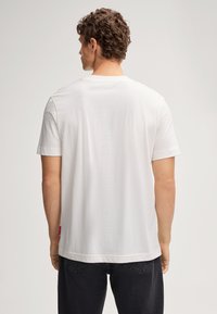 Witte t-shirt met korte mouwen, gemaakt van zachte katoen. Kenmerkt een ronde hals en een lichte textuur, met een klein rood logo-accent op de zoom.