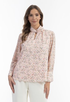 Lyserød bluse med blomsterprint, nøglehuludskæring, lange ærmer og blødt stof. Har fine mønstre af blomster og blade.