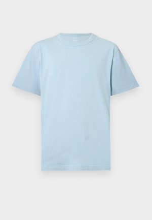 Camiseta de manga corta de color azul claro con cuello redondo y un ajuste relajado, mostrada sobre un fondo blanco liso.