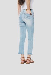 Lichtblauwe denim jeans met een slim fit, voorzien van een decoratief bloemenpatroon op het achterzakje, een ruwe zoom en subtiele vervaging.