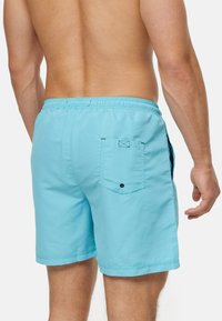 Himmelblaue Badeshorts aus glattem Stoff, mit elastischem Bund, einer hinteren Patztasche mit Knopf und seitlichen Schlitzen für Bewegungsfreiheit.