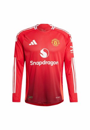 Rode longsleeve trui van lichtgewicht materiaal, met witte strepen op de schouders, een ronde hals en het Manchester United-logo op de borst.