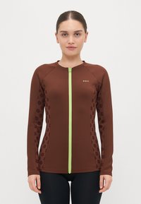 Rudas ilgomis rankovėmis zip-up rashguard'as su tamsiai rudos spalvos gėlių akcentais, turintis žalią užtrauktuką. Lygi tekstūra ir prigludusi forma.