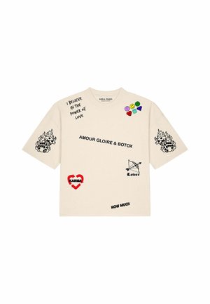 Beiges T-Shirt mit schwarzen Textphrasen einschließlich "I believe in the power of love" und "Amour gloire & botox,", farbigen Emojis und Grafiken von brennenden Würfeln.